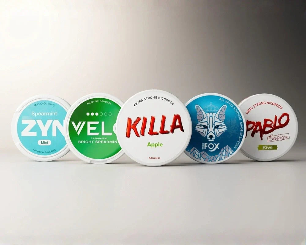 Row of nicotine pouch cans from ZYN, VELO, KILLA, IFOX and PABLO on a neutral background