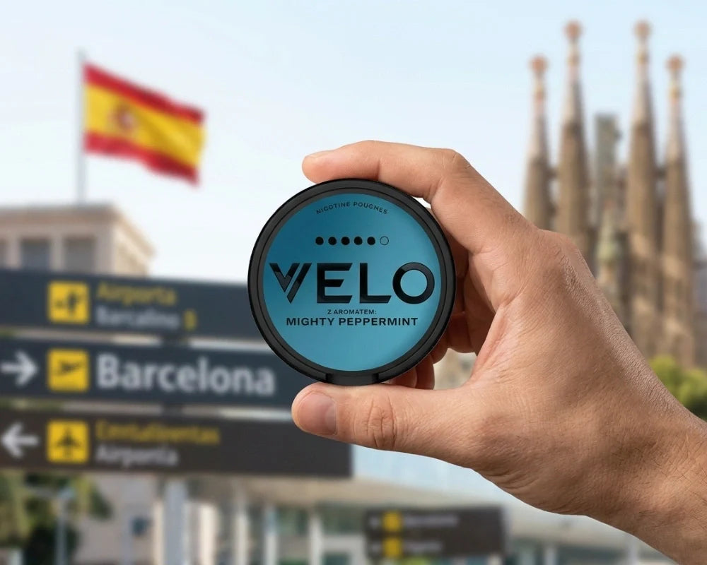 Hand holding a VELO Mighty Peppermint can in front of Barcelona road signs, a Spanish flag and the Sagrada Familia