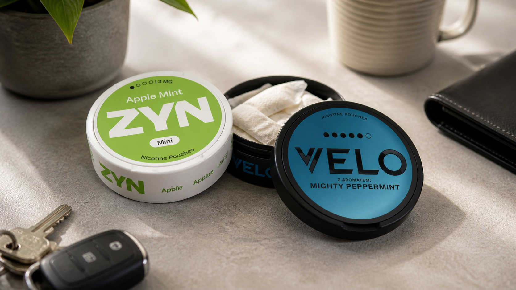Una lata de ZYN Apple Mint y una lata de VELO Mighty Peppermint con una lata abierta, llaves de coche y una cartera sobre una encimera